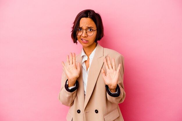 Young business donna di razza mista isolata su sfondo rosa, rifiutando qualcuno che mostra un gesto di disgusto.