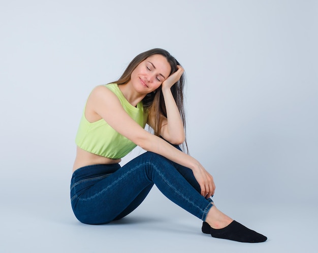 Young girl is wishing by sitting on floor on white background