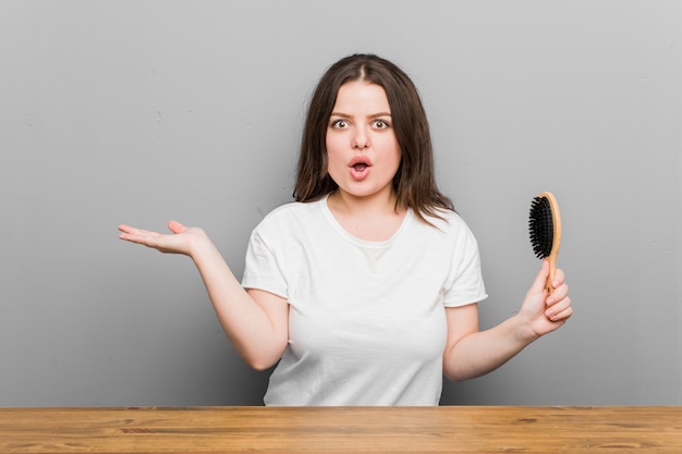 Young plus size donna formosa in possesso di una spazzola per capelli colpito