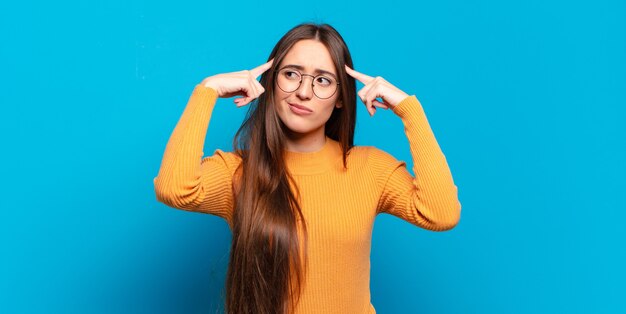 Young pretty casual woman looking concentrated and thinking hard on an idea, imagining a solution to a challenge or problem