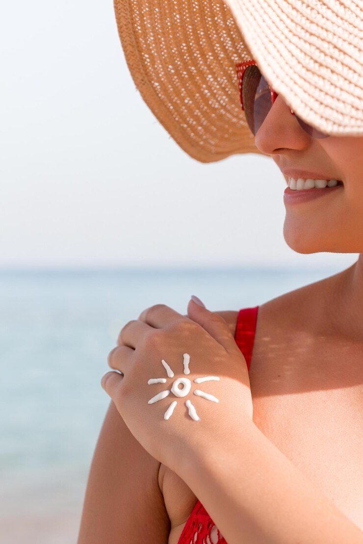 Photo young woman with sun shape on her hand made of sunscreen at the beach