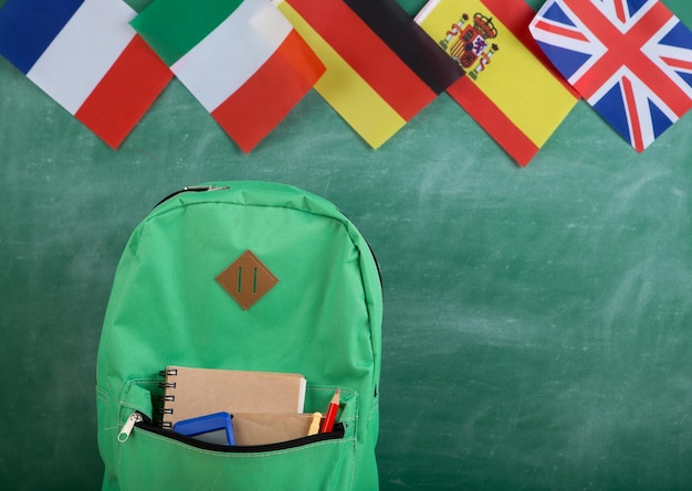 Zaino bandiere della Spagna Francia Gran Bretagna e altri paesi e materiale scolastico sullo sfondo della lavagna