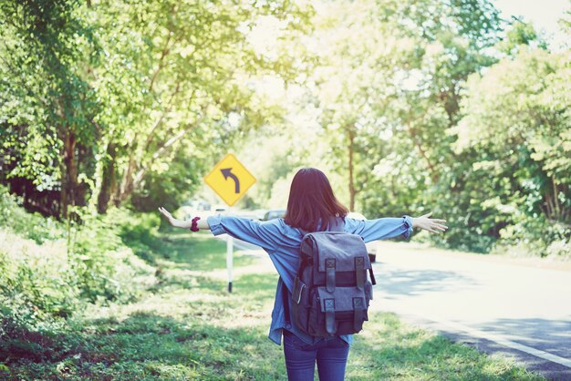 Zaino bella donna rilassante sulla strada. Tempo di vacanze ed estate.