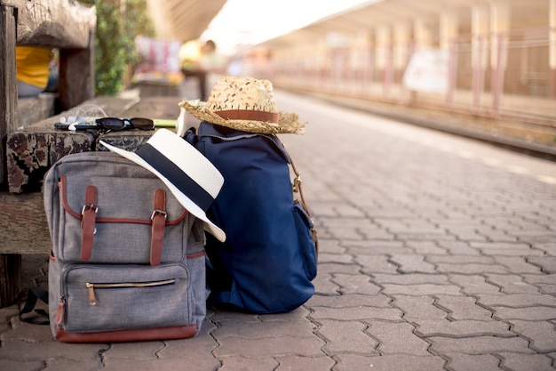 Zaino con cappello, mappa, occhiali da sole, auricolare e smartphone nella stazione ferroviaria
