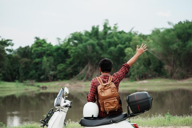 Zaino in spalla hipster in sella a uno scooter su strada Viaggia in scooter vita lenta in vacanza tempo di riposo