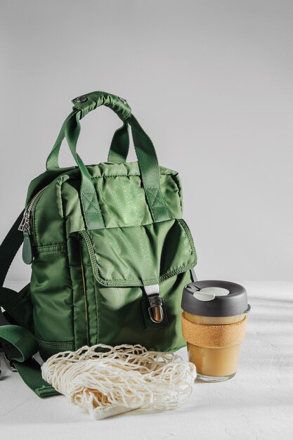 Zaino verde con tazza da caffè riutilizzabile. Stile di vita sostenibile. Zero sprechi, concetto plastic free.