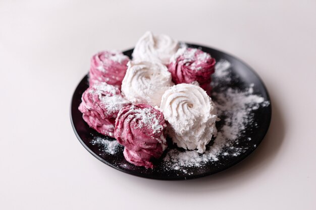 Zefiro. Dolci colorati sul primo piano della banda nera. Deliziosa pasticceria, dolce fatto in casa a colazione