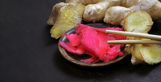 Zenzero rosa marinato e radice fresca sul tavolo. condimento per sushi tradizionale. copia spazio