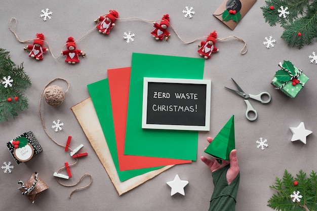 Zero rifiuti natalizi, vista piana, vista dall'alto su carta artigianale con ghirlanda tessile, regali incartati, lavagna nera con testo "Zero Waste Christmas" su carta. Decorazioni natalizie ecologiche