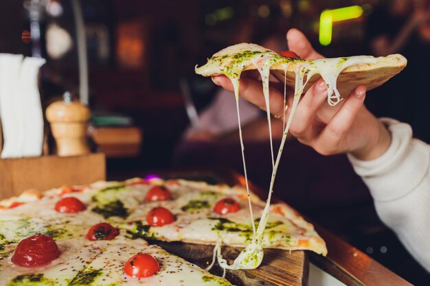 Zolla della holding della giovane donna con pizza saporita, vista alta vicina.