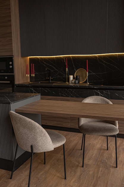 Zona cucina in un interno elegante e costoso di una casa di lusso con un design moderno nero e marrone scuro con finiture in legno e luce a led