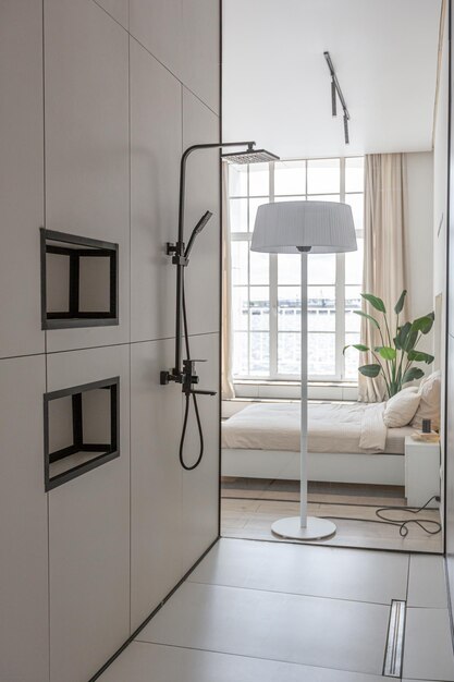 Zona doccia elegante e alla moda in un design di lusso moderno e minimalista di una casa costosa in una giornata di sole in bianco con uno specchio rotondo e un lavandino a pavimento