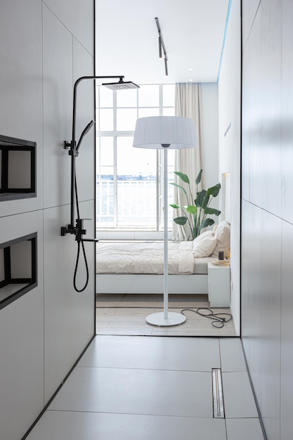 Zona doccia elegante e alla moda in un design di lusso moderno e minimalista di una casa costosa in una giornata di sole in bianco con uno specchio rotondo e un lavandino a pavimento
