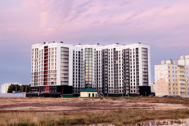 Zona residenziale moderna al tramonto in tarda serata. Tardo autunno. Fango e pozzanghere ai margini della città. Edifici residenziali multipiano. Mutuo per giovani famiglie.