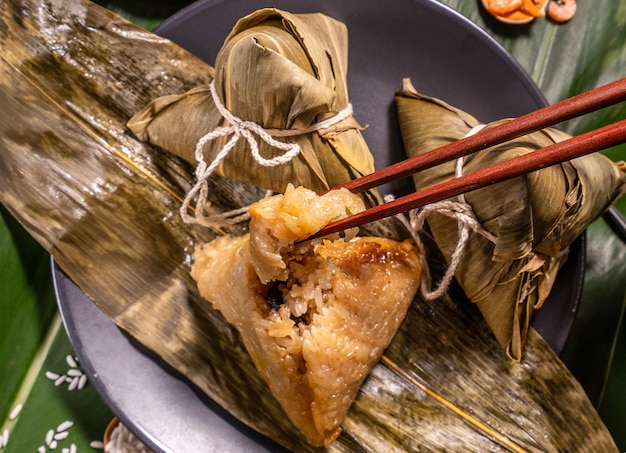 Zongzi donna mangiare gnocchi di riso al vapore sul tavolo verde cibo di sfondo in dragon boat festival duanwu concept close up copia spazio vista dall'alto laici piatta