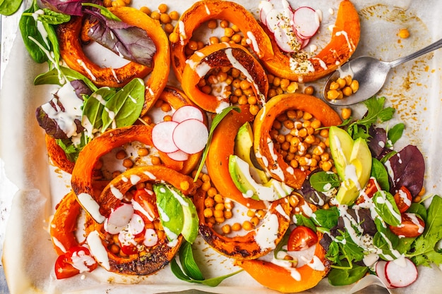 Zucca al forno con ceci su una teglia con avocado