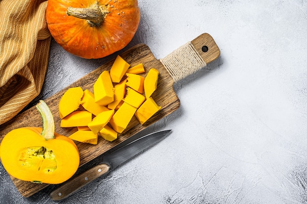 Zucca arancione cruda affettata su un tagliere. sfondo bianco