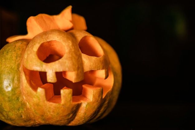 Zucca arancione di Halloween con la faccia buffa sul buio