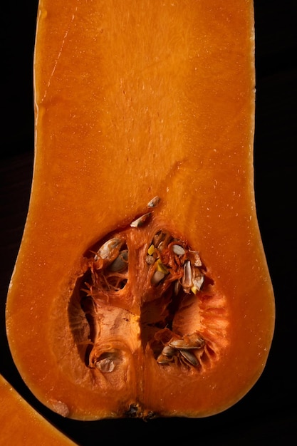 Zucca arancione matura affettata da vicino sullo sfondo di legno