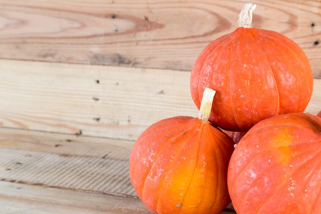 zucca arancione piccola sullo sfondo della tabella di legno