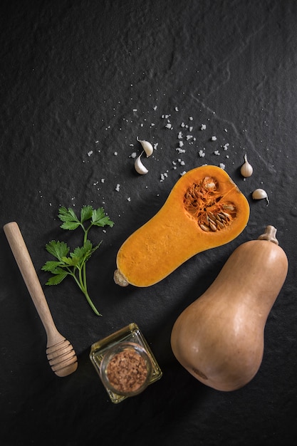 Zucca butternut biologica con spezie e ingredienti per fare su una lavagna nera,