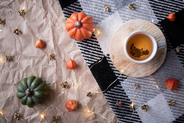 Zucca con una tazza di tè su un plaid a scacchi autunno ottobre arredamento piatto lay