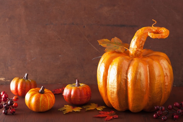 Zucca decorativa di cartapesta e foglie di autunno dorate per il ringraziamento di Halloween