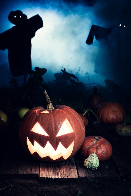 Zucca di Halloween arancione con nebbia blu e spaventapasseri