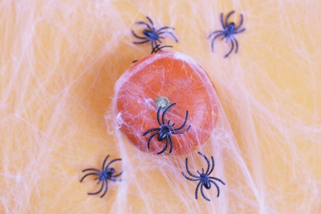 Zucca di Halloween con ragnatela e ragni neri su sfondo arancione