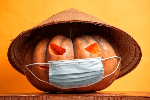 Zucca di Halloween in una maschera medica su uno sfondo arancione