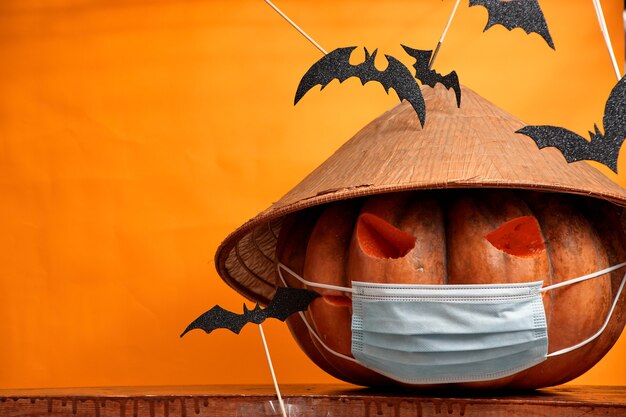 Zucca di Halloween in una maschera medica su uno sfondo arancione
