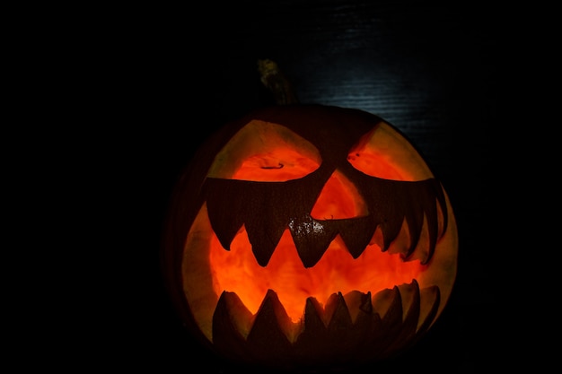 Zucca di halloween luminosa spettrale su sfondo nero