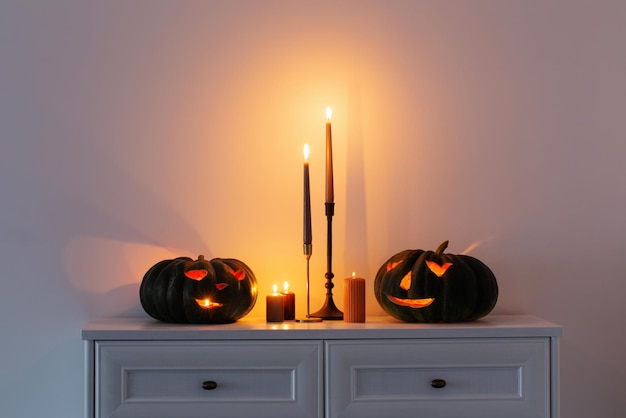 Zucca di Halloween nera con candele accese in interni bianchi