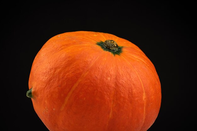 Zucca di Hokkaido o Kuri rosso su sfondo nero. Foto di concetto di cibo di verdure fresche autunnali