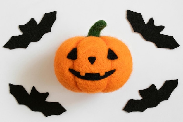 Zucca di lana di Halloween e pipistrelli su sfondo bianco