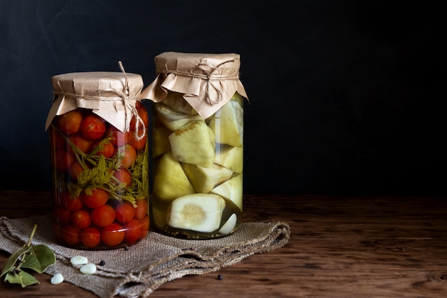 Zucca e pomodori marinati in un barattolo su una tavola di legno