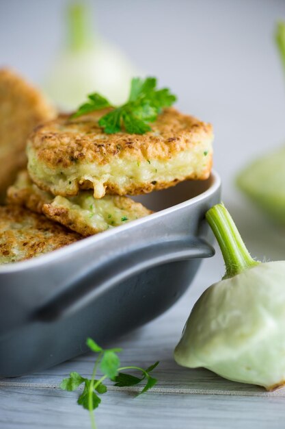 Zucca fritta di verdure e cotolette di zucchine in forma di ceramica su un tavolo di legno chiaro