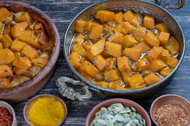 Zucca gialla al forno con miele, anice, olio d'oliva e spezie su un piatto sul tavolo di legno Cibo vegetariano Closeup