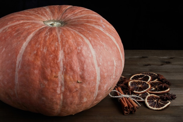 Zucca organica fresca e spezie di Natale su sfondo scuro.