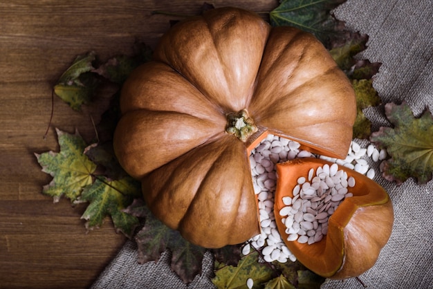 Zucca sdraiata su un tavolo di legno con viburno e semi