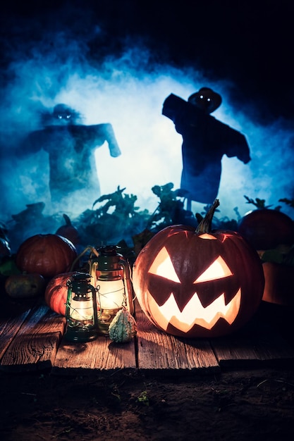 Zucca spaventosa di Halloween con nebbia blu e spaventapasseri