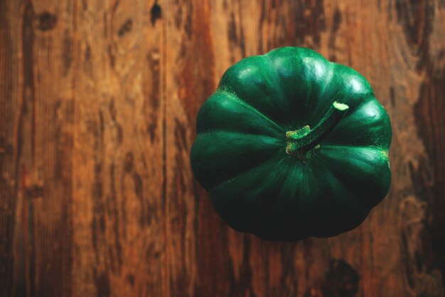 Zucca verde con gambo sul tavolo di legno scuro.