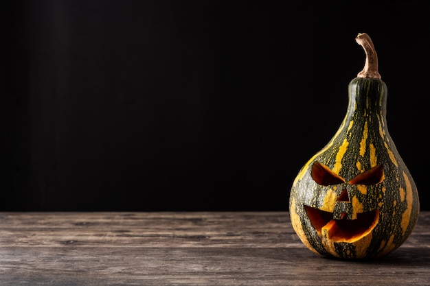 Zucca verde di Halloween su tavola di legno e sfondo nero