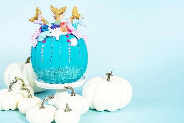 Zucche artigianali di Halloween decorate con code di sirena, glitter e strass scintillanti su sfondo blu.