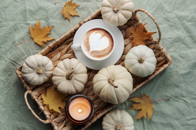 Zucche bianche caffè e foglie d'autunno su un vassoio di vimini