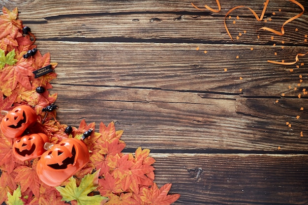 Zucche di Halloween con foglie di autunno cadono su legno