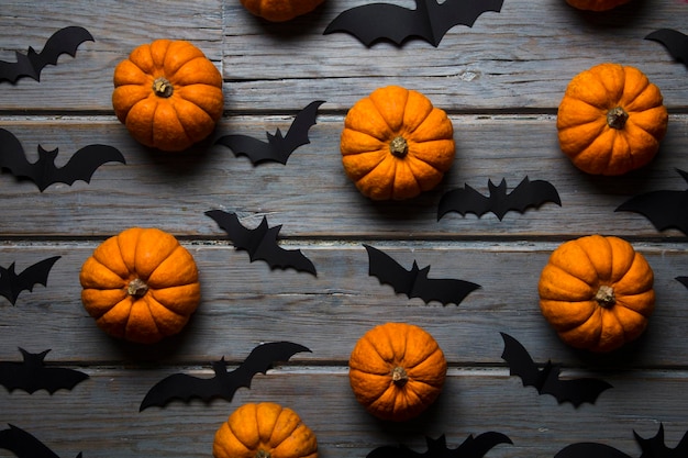 Zucche di Halloween e pipistrelli vampiri neri su uno sfondo di legno