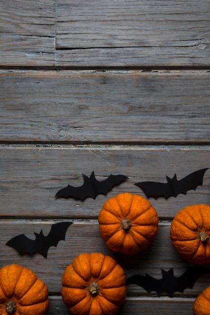 Zucche di Halloween e pipistrelli vampiri neri su uno sfondo di legno