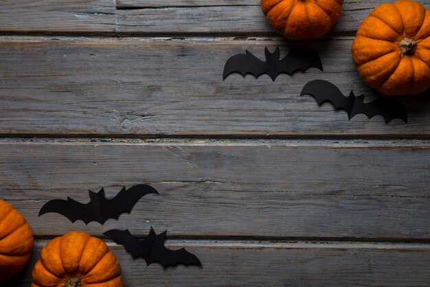 Zucche di Halloween e pipistrelli vampiri neri su uno sfondo di legno