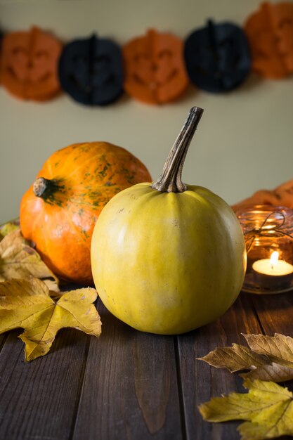 Zucche di Halloween sulla tavola di legno con la candela e le foglie di giallo di autunno